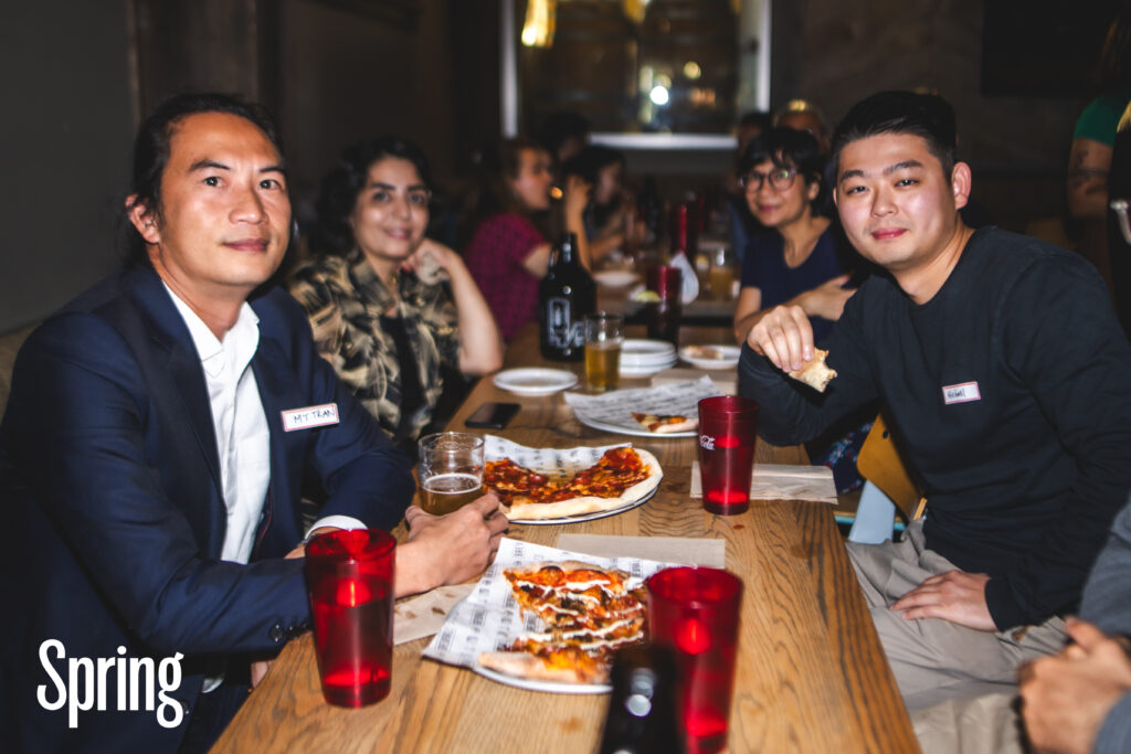 People gathered at a table eating pizza together at a Spring event