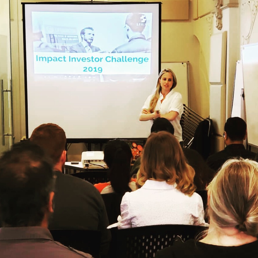 A person giving a presentation on Spring's 2009 Impact Investor Challenge to an audience.