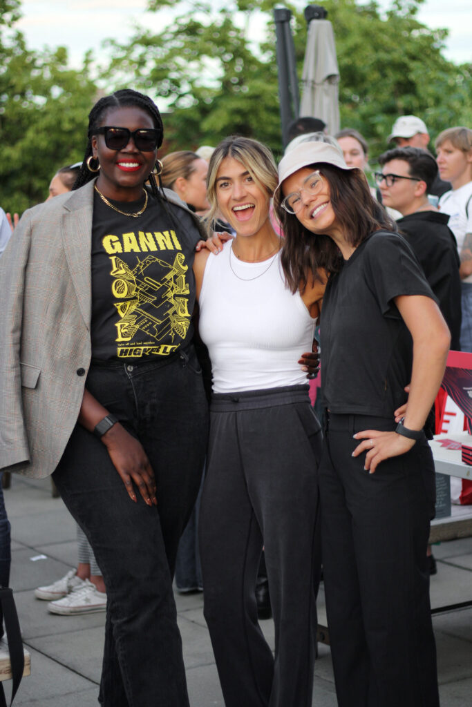 Three smiling people pose together at an outdoor event