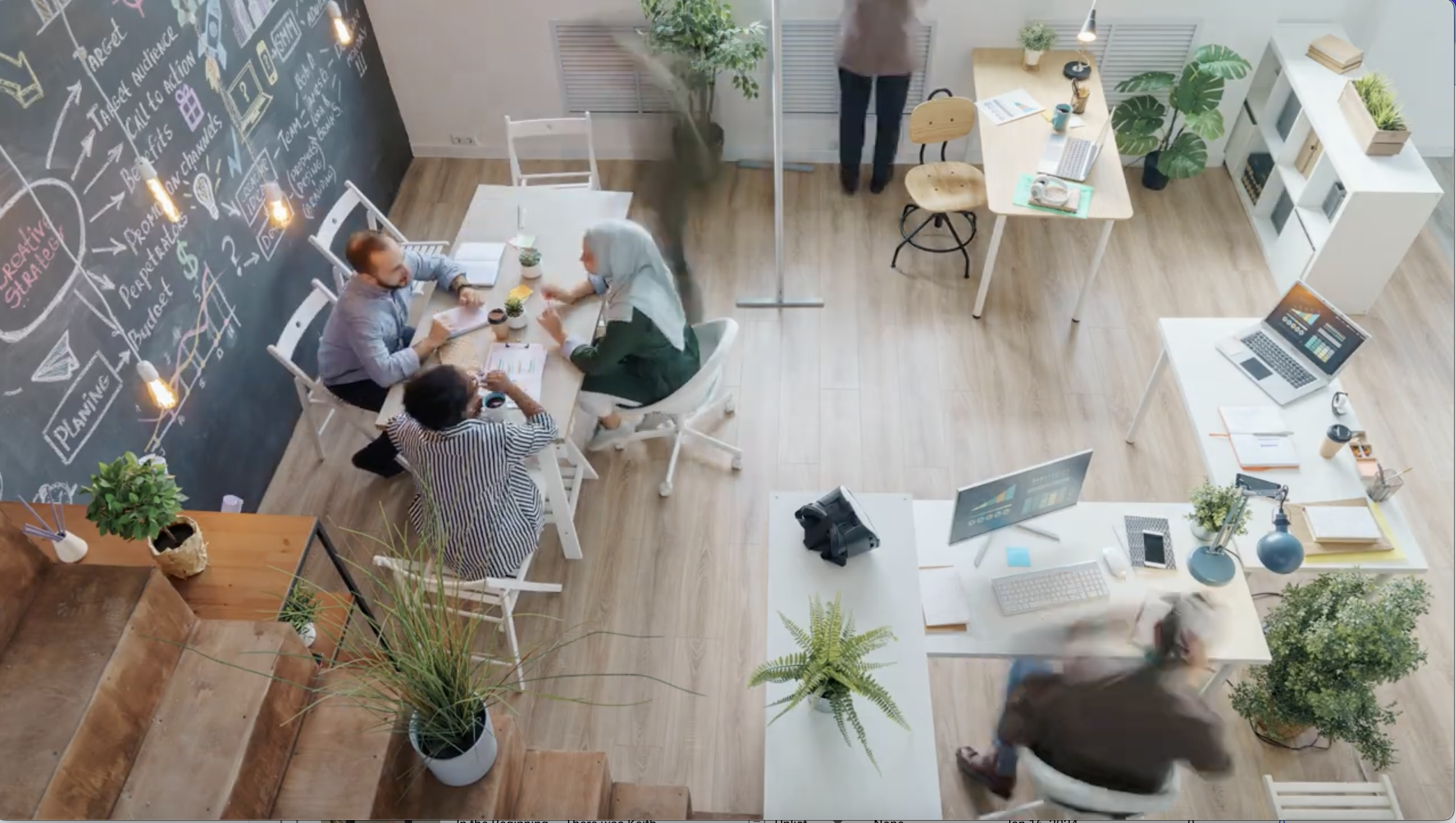Overhead shot of people working in an airy office filled with plants