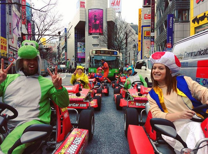 Christine dressed as Toad from Super Mario Bros, riding a go-kart in Tokyo alongside others who are dressed up