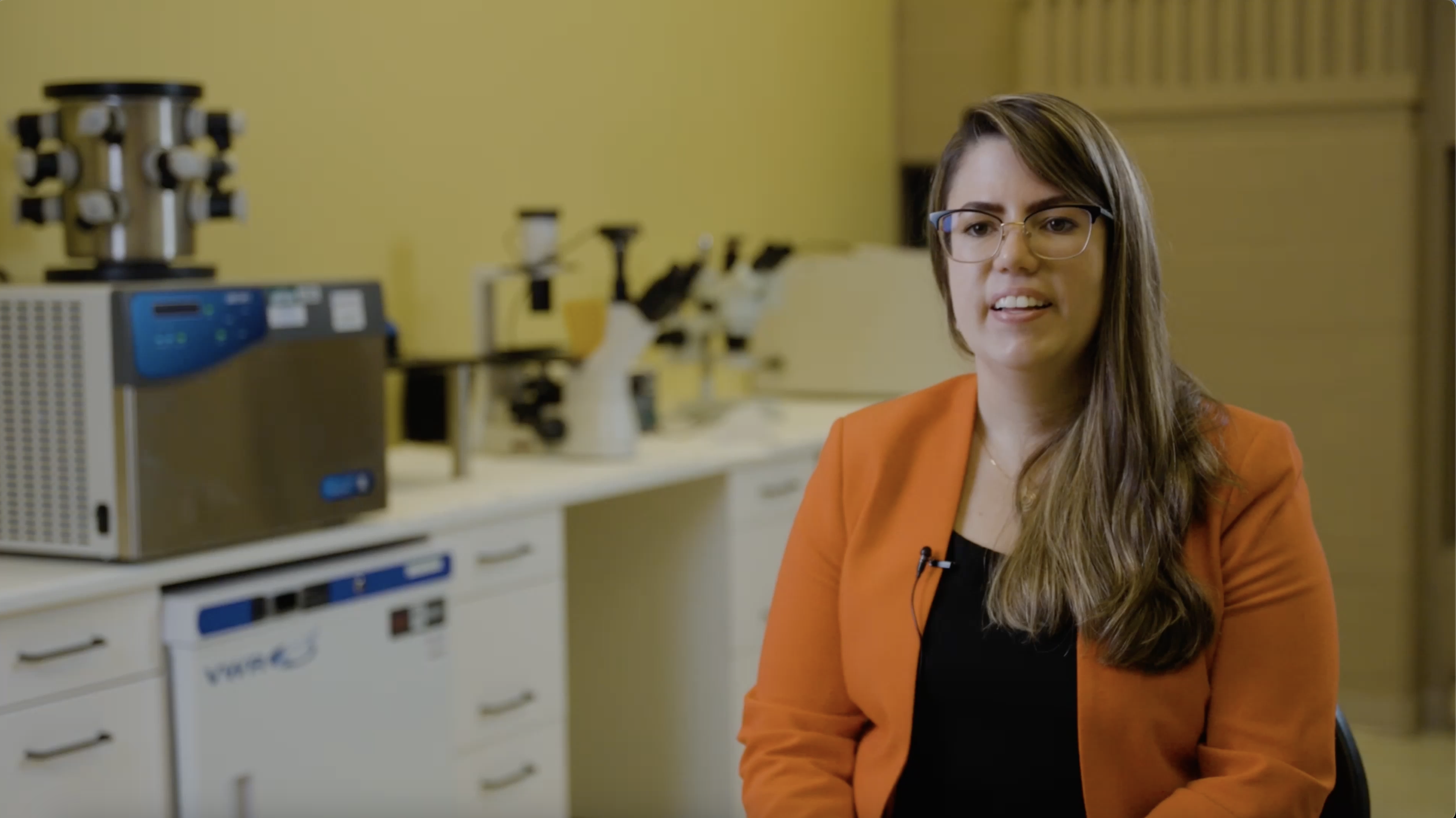 Dr. Karolina Valente of VoxCell BioInnovation, wearing an orange jacket and sitting in a laboratory