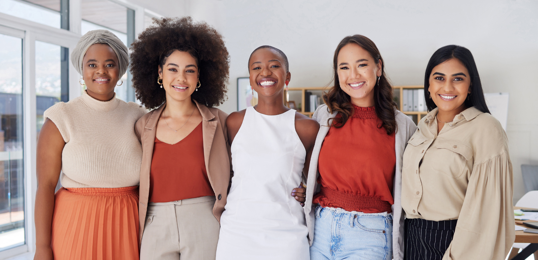 5 women with their arms around each other smiling in a business setting